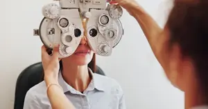 A woman is having her eyes checked by an optometrist using an autorefractor machine.