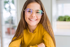 Young girl with brown hair and sunglasses smiling at the camera