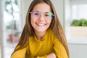 Young girl with brown hair and sunglasses smiling at the camera