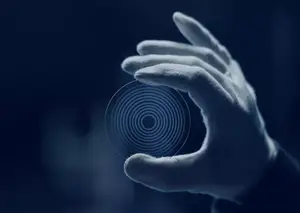 Image of a hand holding a transparent circular object with a spiral design in the middle