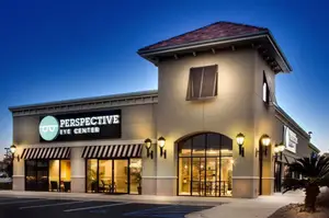 Front of Perspective Eye Center building with signage, lights, and palm tree at night.