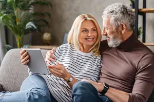 An older couple looking at a tablet together on a couch