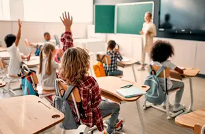 A classroom with students and a teacher, one student is raising their hand to ask a question