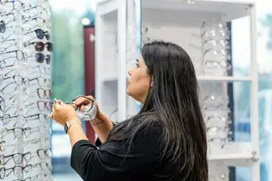 A woman is looking at eyeglasses inside a shop