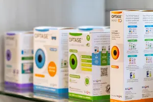 A row of eye care product boxes with the brand name OPTASE and the word PROTECT on the top left corner of the boxes are displayed on a glass shelf
