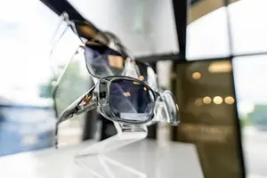 A pair of sunglasses on a clear stand in a shop window