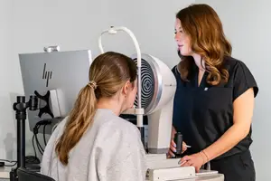 A woman is having her eye examined by another woman in an eye clinic room.