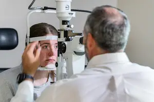 Eye doctor examining a woman's eyes with an ophthalmoscope