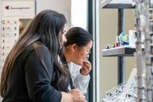 Two women are looking at glasses in a store.