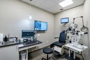 The interior of an eye clinic examination room with equipment and monitors displayed on the wall