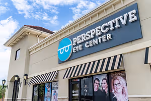A photo of the Perspective Eye Center building with a sign displaying the name, two lamps on the wall, and two people in glasses on the glass door