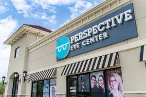A photo of the Perspective Eye Center building with a sign displaying the name, two lamps on the wall, and two people in glasses on the glass door