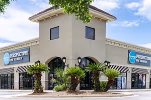 A building with the words Perspective Eye Center on it, surrounded by palm trees and awnings.