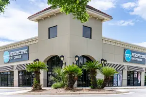 A building with the words Perspective Eye Center on it, surrounded by palm trees and awnings.