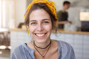 Woman with a yellow scarf and necklace smiling at the camera