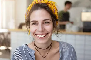 Woman with a yellow scarf and necklace smiling at the camera