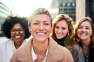 Group of four women standing in front of a building smiling