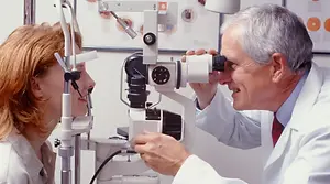 Optometrist examining a patient's eye with a slit lamp