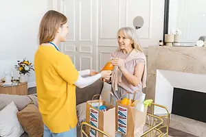 An elderly woman receiving a grocery delivery in her living room