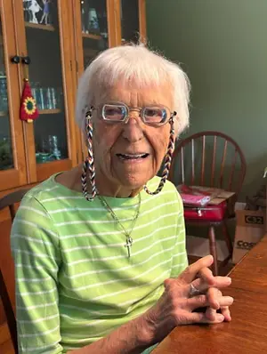 Elderly woman smiling while wearing eyeglasses with a decorative chain