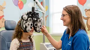 A young girl has her eyes examined by an optometrist