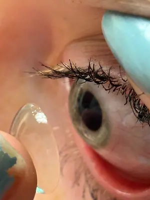 A close up of an eye with a contact lens being inserted