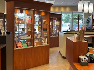 A glass display case in a beauty salon features a variety of hair care products, magazines, and promotional materials, with a warm and inviting interior design.