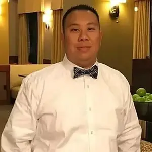 A man wearing a white shirt and a bow tie in a hotel room