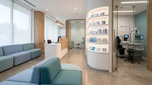 The interior of a modern medical clinic with a reception area, examination room, and display shelves.