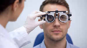 An optometrist adjusts a patient's vision testing device in a clinic setting