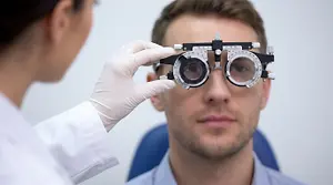 An optometrist adjusts a patient's vision testing device in a clinic setting