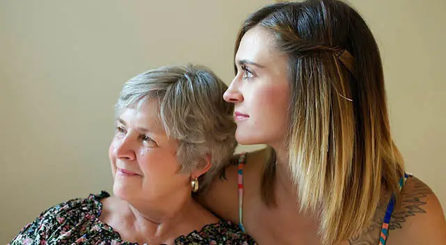 An older woman with short gray hair and a younger woman with long brown hair looking at each other