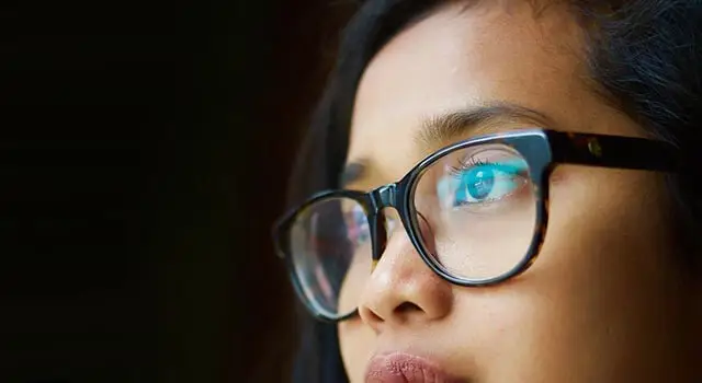 woman with glasses and blue eyes looking upward