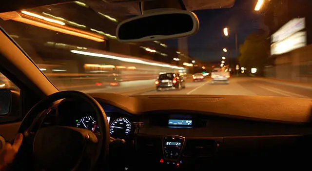 a car driving on a city road at night