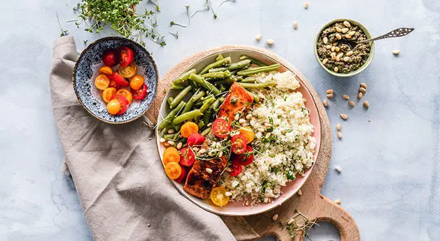 Healthy Salmon and Cauliflower Rice Recipe: A Plate of Salmon, Green Beans, Tomatoes, and Cauliflower Rice on a Blue Tablecloth